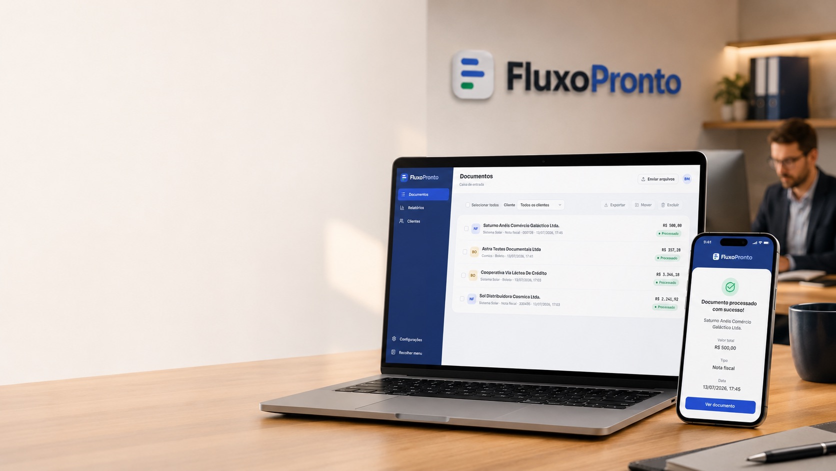 Estação de trabalho com o FluxoPronto aberto no notebook e a confirmação de documento processado no celular